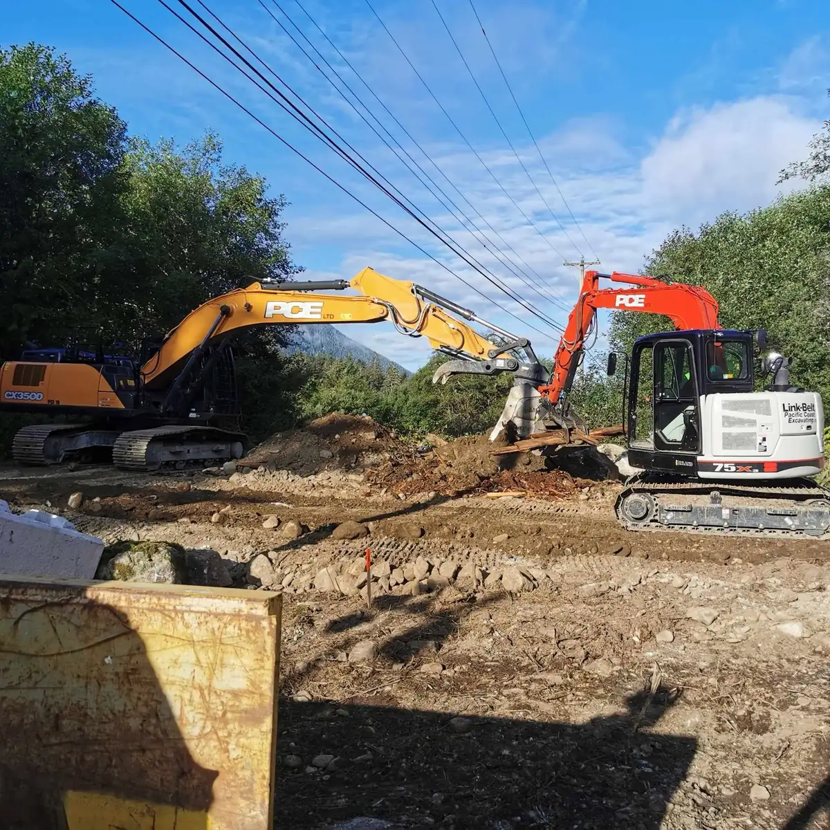 Two PCE excavators working beside power lines on the access road