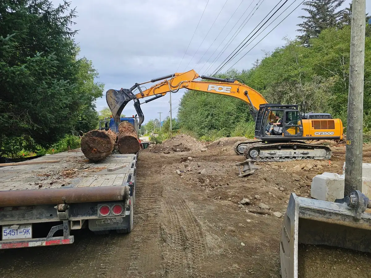 PCE excavator loading logs onto a flat-deck truck