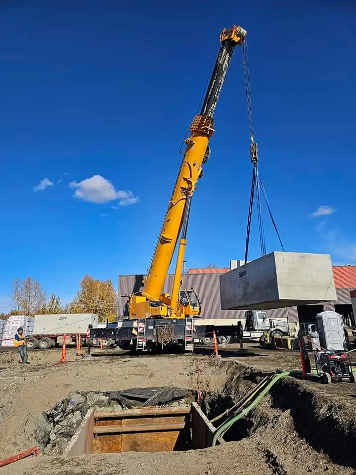 Crane lifting a precast vault from the truck