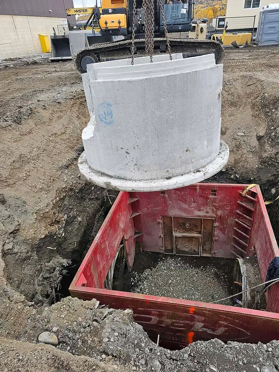 Manhole section lowered into a shoring box