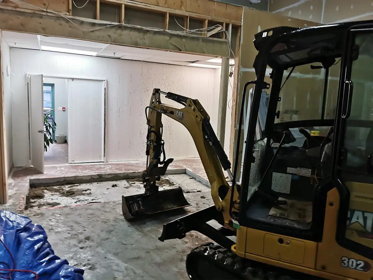 Mini excavator breaking out the floor inside the unit